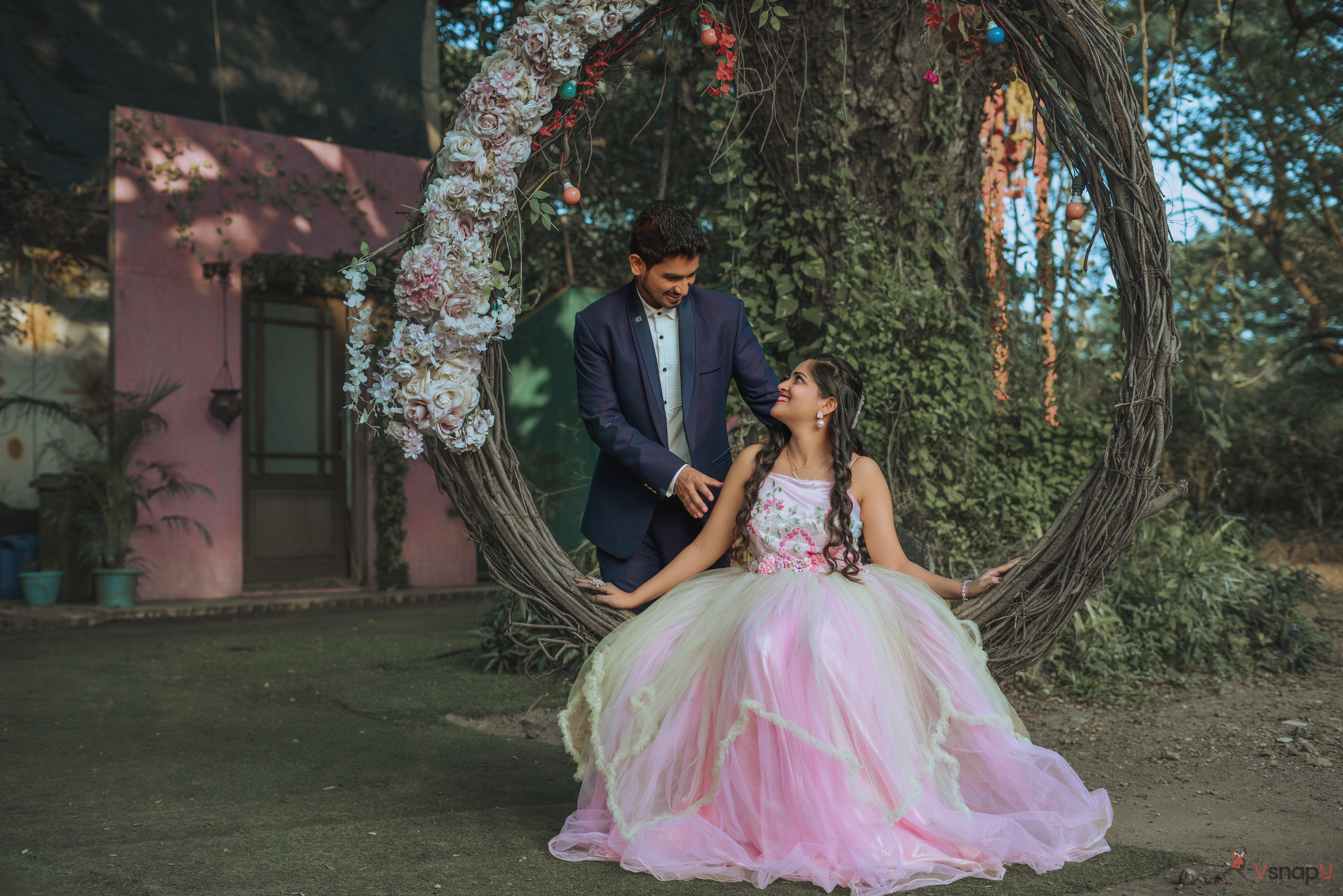 A cozy moment in the garden as an ethnic-wear couple sits on a handmade swing chair, looking into each other’s eyes with affection.